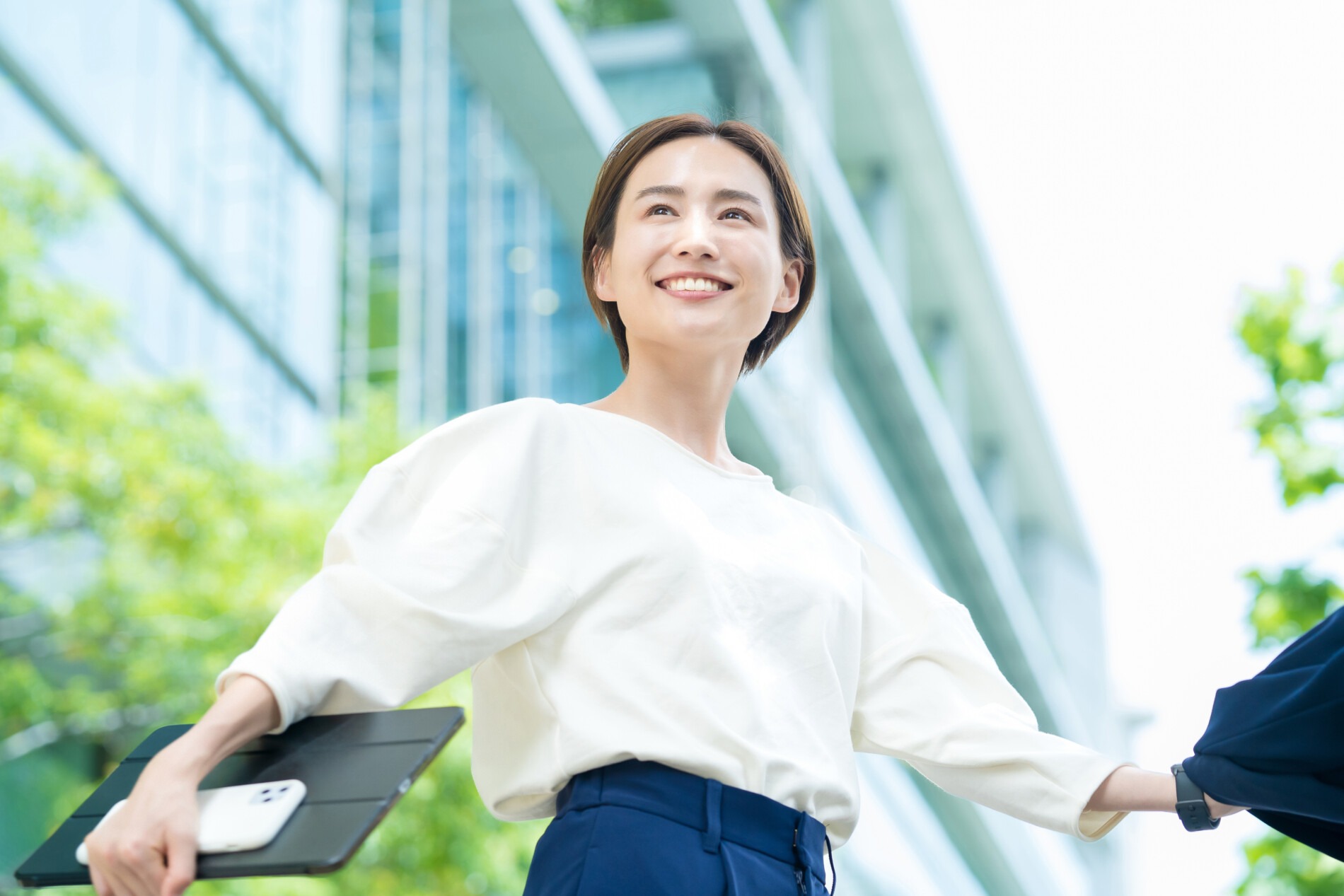 明るいオフィスを背景にタブレットを持つビジネスパーソン
