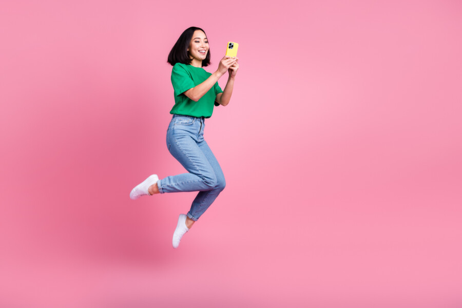 ピンクの背景でスマートフォンを使う人物