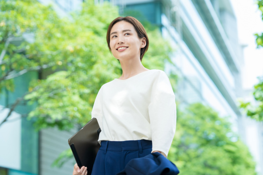オフィス街に立つ笑顔の女性