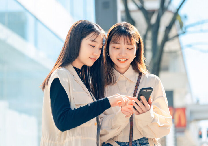 街中でスマホを見る友達同士の若い女性