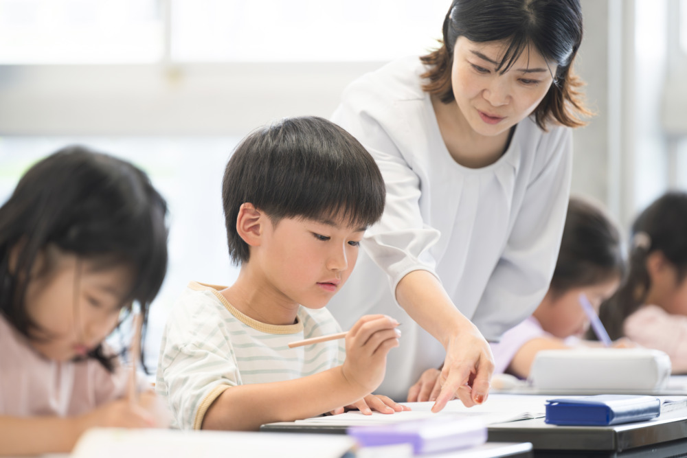 学校の教室で勉強する子供たちと指導する先生　クローズアップ