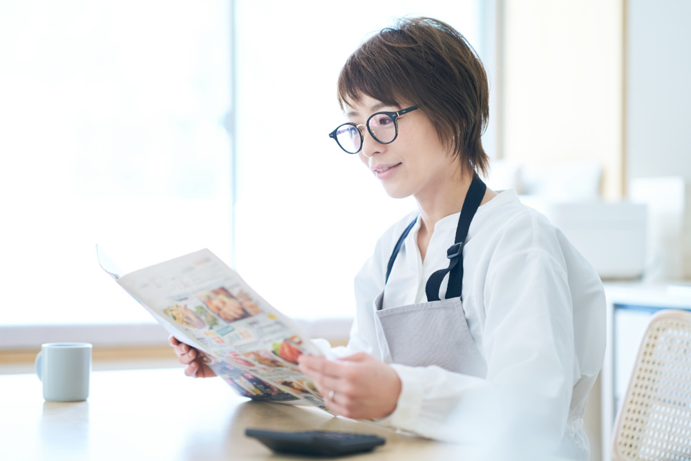 メガネをかけて広告チラシを見る女性