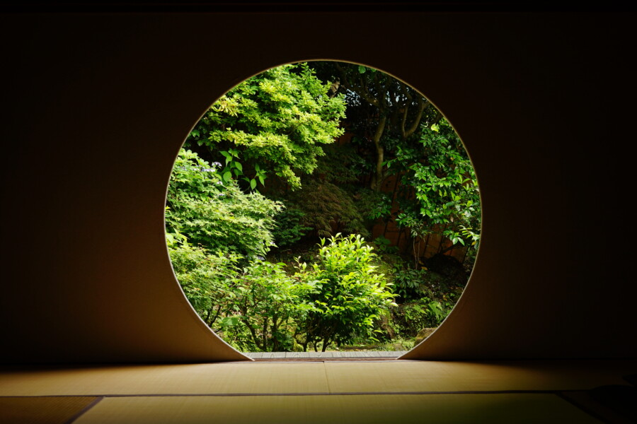 Looking at Japanese garden thru Round window in Japanese archite