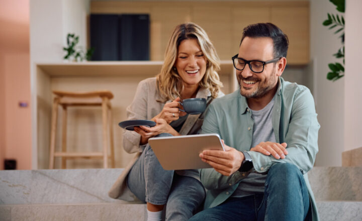 Happy couple using digital tablet while relaxing at home.
